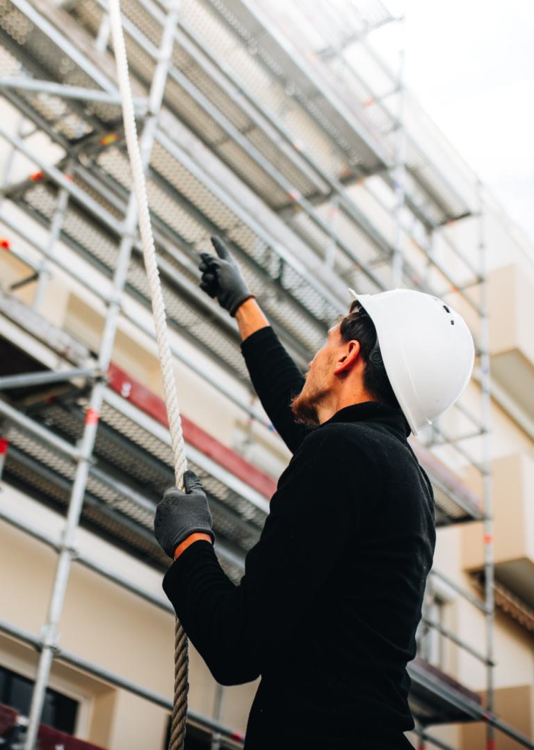 Travailleur en casque tirant une corde sur chantier.