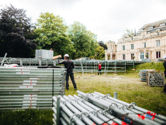 ouvriers montant une structure métallique devant château