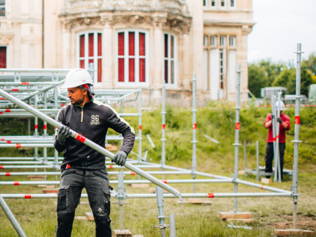 Ouvrier montant des échafaudages devant bâtiment historique